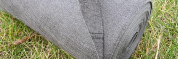 Nahaufnahme von der Rootguard Wurzelschutzvliesrolle in grau auf dem Rasen