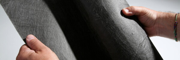 Mann hat leicht aufgerollte schwarze Rootguard Wurzelschutzvlies Rolle in der Hand