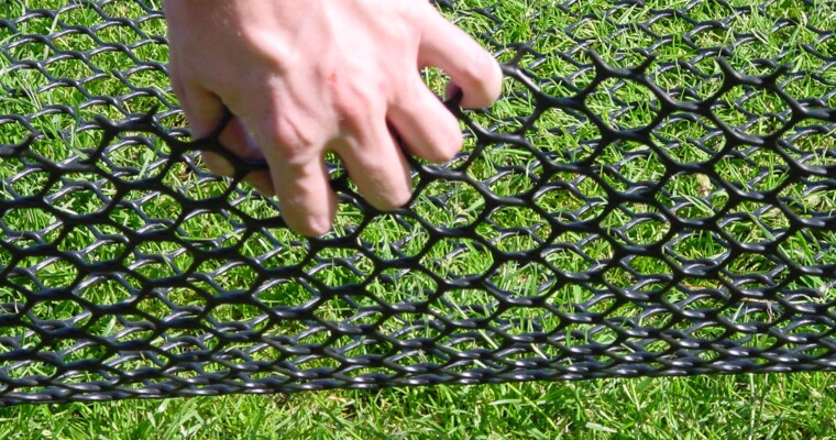 TERRAM TurfProtecta Rasenschutzgitter wird mit der Hand angehoben um die Gitterstruktur zu verdeutlichen