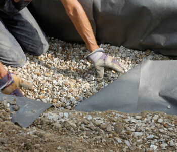 Mann legt Steine über das Rootguard Wurzelschutzvlies