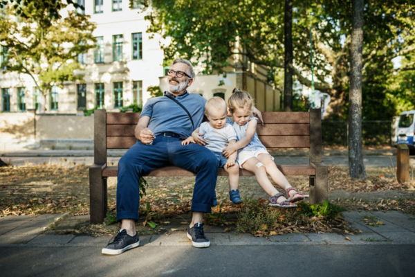 Familie sitzt auf brauner Hyde Park Bank aus hanit Recyclingkunststoff in einer grünen Stadt.